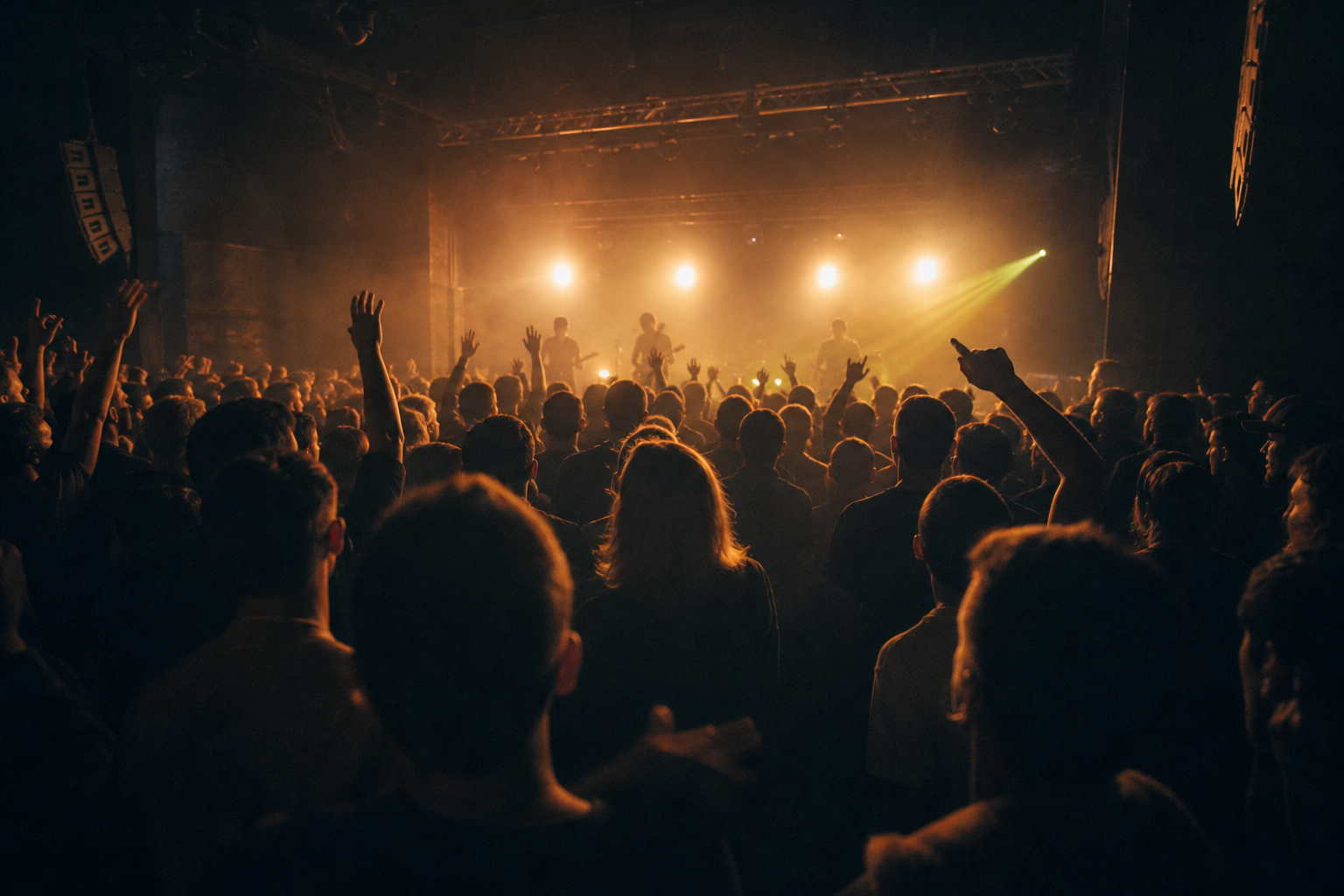 A live band performing through warm stage haze for a packed crowd in an intimate venue.